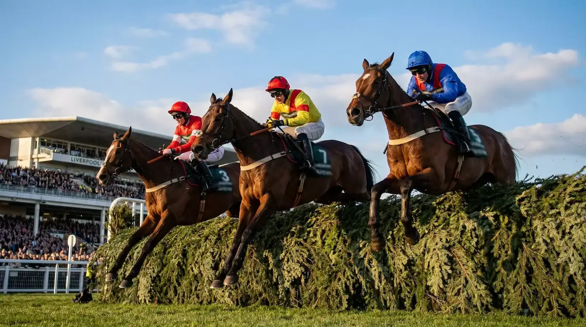 Horses jumping fence at Aintree during Grand National steeplechase race